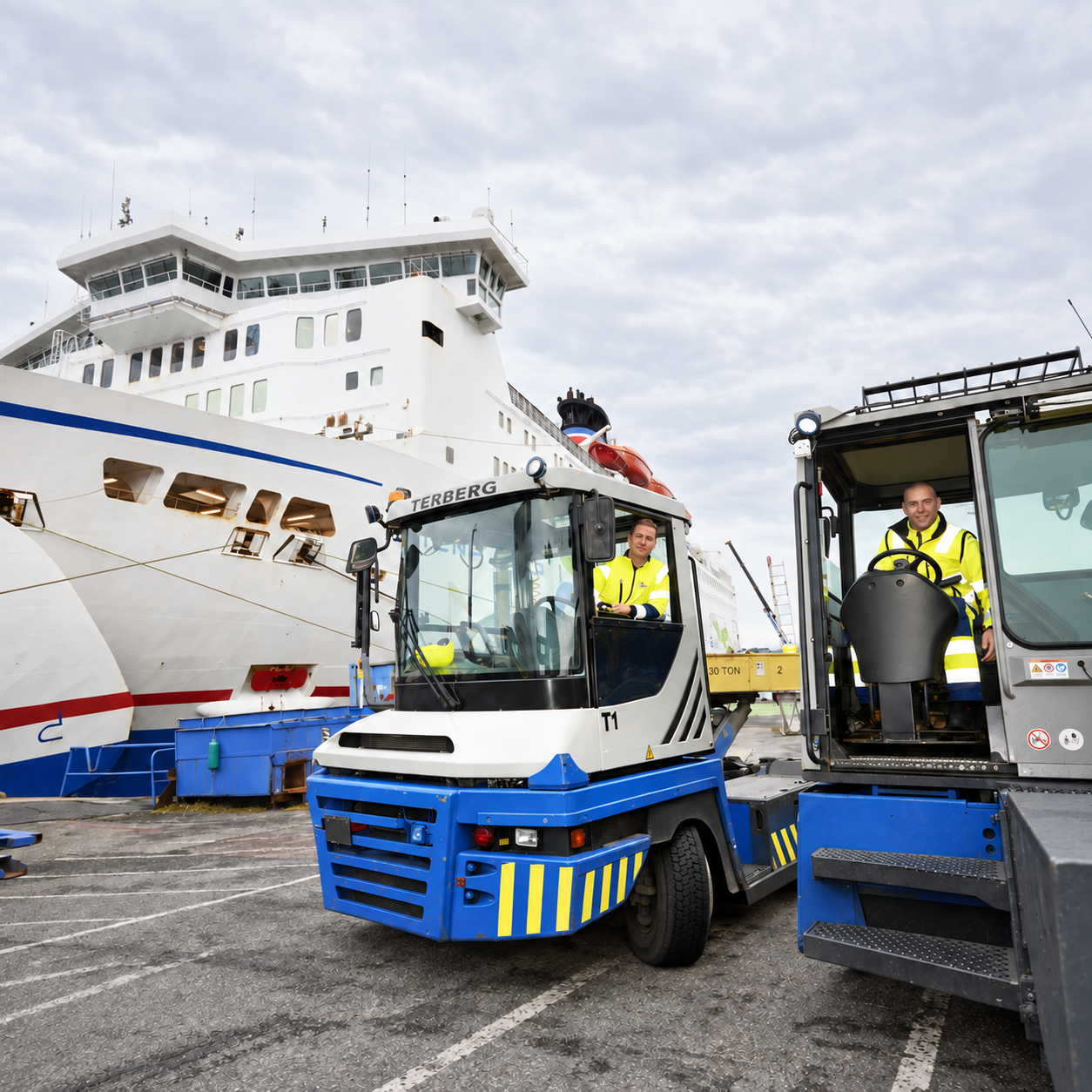 Zwei Tugmaster mit ihren Fahrern neben einer Fähre im Hafen