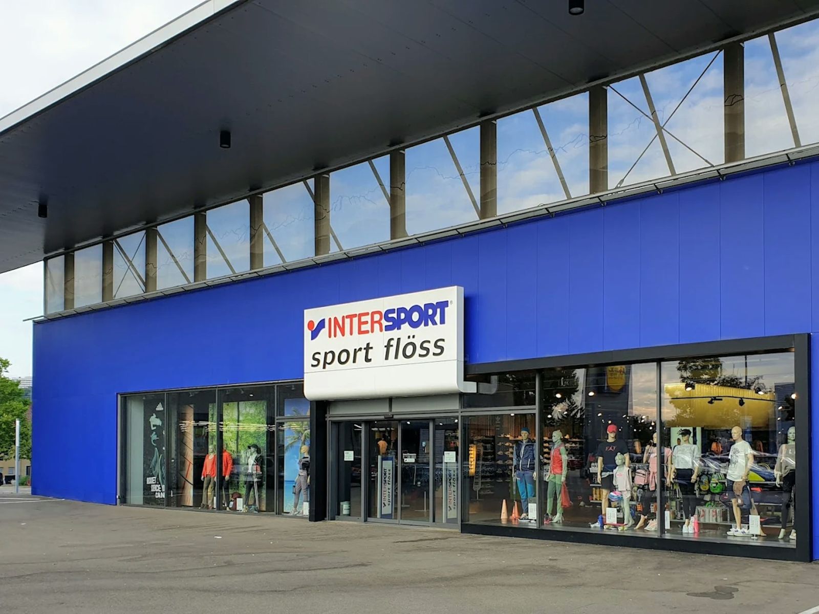 Eingang der Filiale von INTERSPORT Sport Flöss mit blauer Fassade